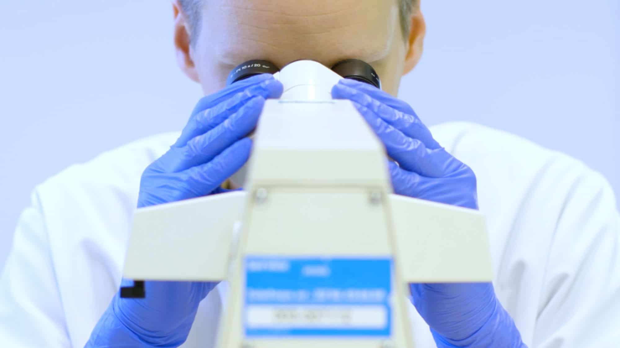Een laborant analyseert bloed met hulp van een microscoop